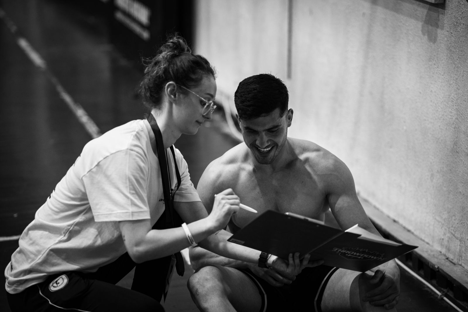Coach reviewing a training program on a clipboard with an athlete in the gym